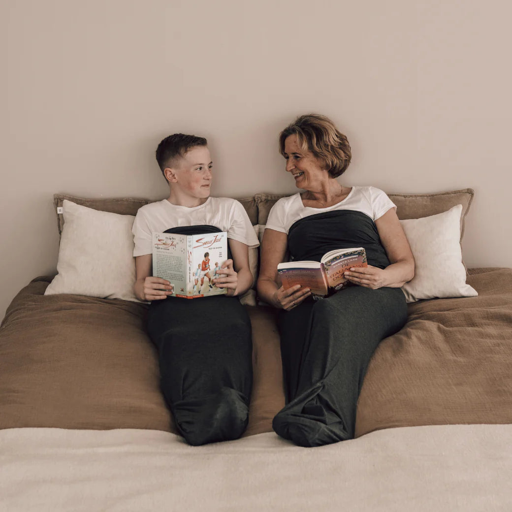 Two people sitting on a bed reading